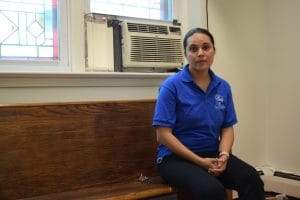 latino woman sitting on brown bench alone looking at camera